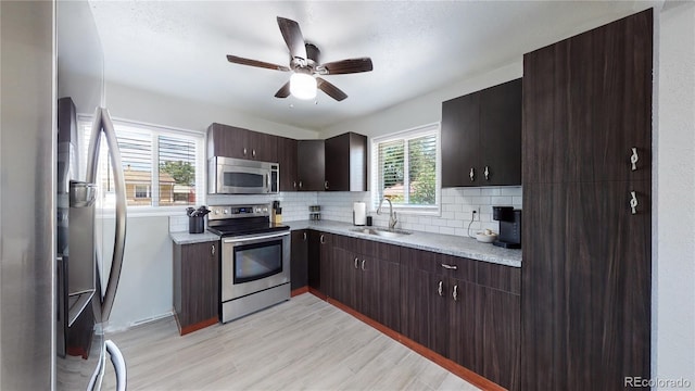 kitchen with dark brown cabinetry, sink, light wood-type flooring, stainless steel appliances, and decorative backsplash