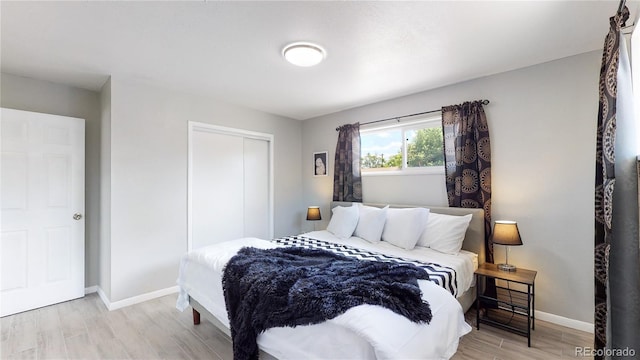 bedroom with light hardwood / wood-style floors and a closet