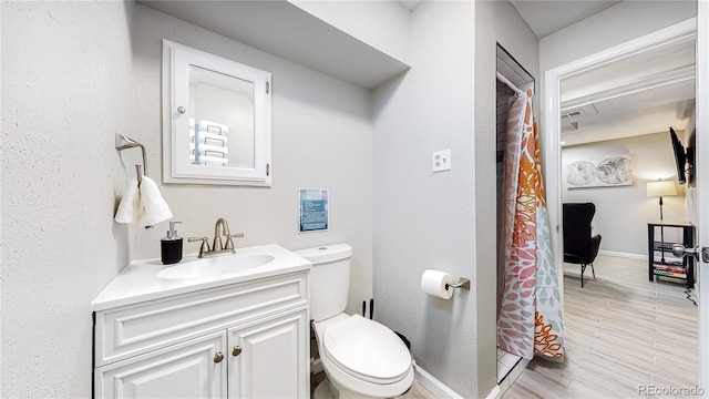 bathroom featuring wood-type flooring, toilet, curtained shower, and vanity