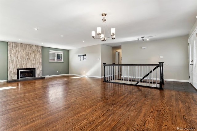 unfurnished living room with a notable chandelier, dark wood-type flooring, and a fireplace