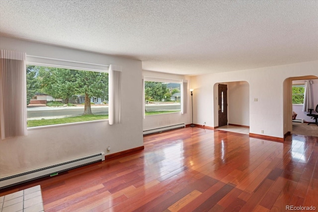 unfurnished room with hardwood / wood-style floors, a textured ceiling, and a baseboard radiator