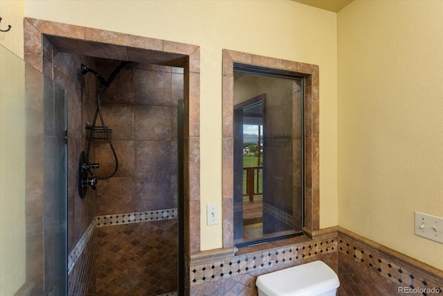 bathroom with tiled shower, tile walls, and toilet