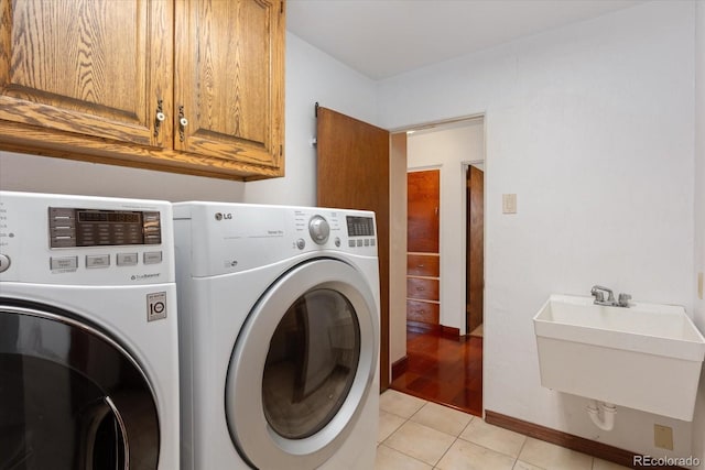 washroom with washing machine and dryer, sink, light tile patterned flooring, and cabinets