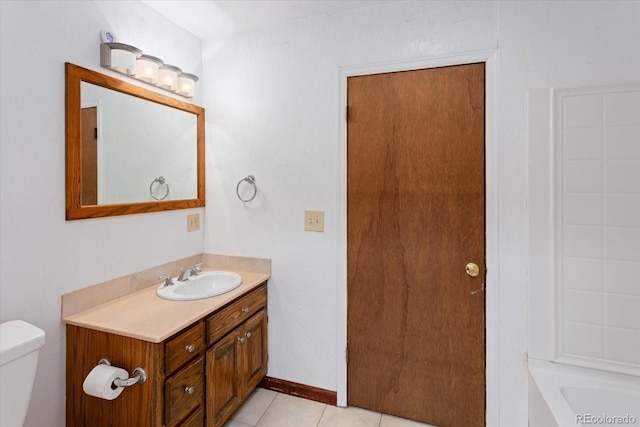 bathroom featuring tile patterned floors, a tub, vanity, and toilet