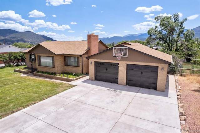 ranch-style house with a mountain view, a front yard, and a garage