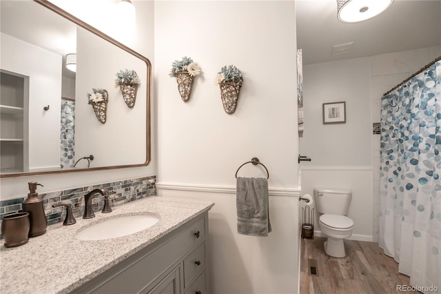 10991 E Vassar Dr, Aurora, CO 80014 - full bathroom with toilet, vanity, wood finished floors, tasteful backsplash, and a shower with shower curtain