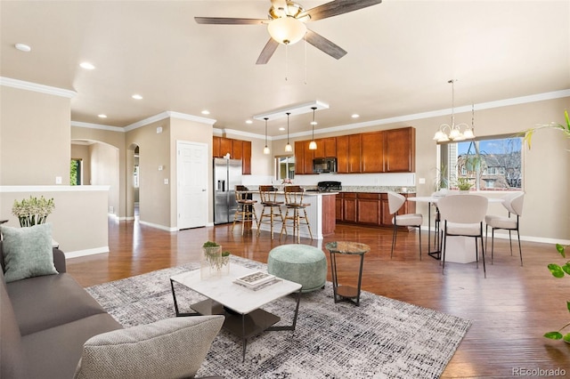 living area featuring crown molding, baseboards, dark wood-style flooring, and arched walkways