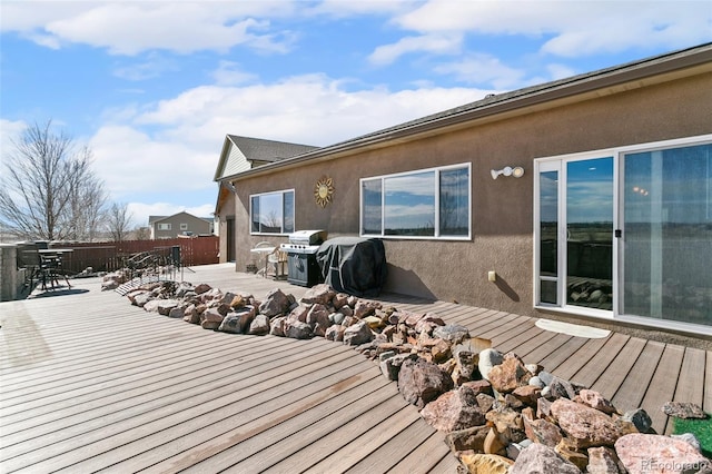 wooden terrace with grilling area, outdoor dining space, and fence