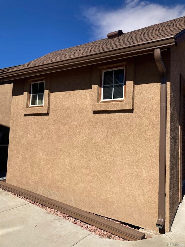 view of home's exterior with stucco siding and a shingled roof