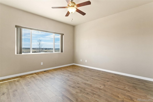 empty room featuring visible vents, wood finished floors, and baseboards