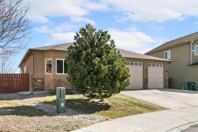 view of front of house with stucco siding, driveway, stone siding, fence, and a garage