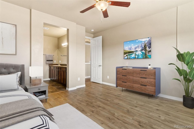 bedroom featuring ensuite bath, wood finished floors, baseboards, and ceiling fan