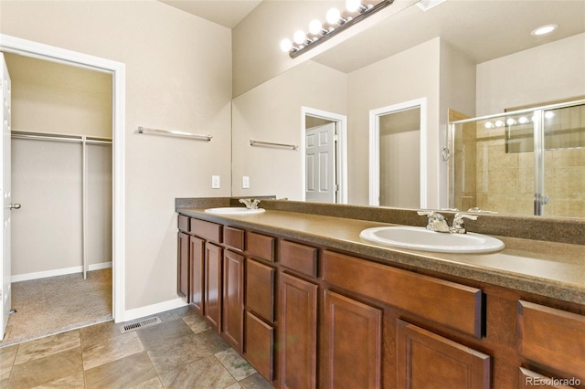 bathroom featuring visible vents, a shower stall, a walk in closet, and a sink