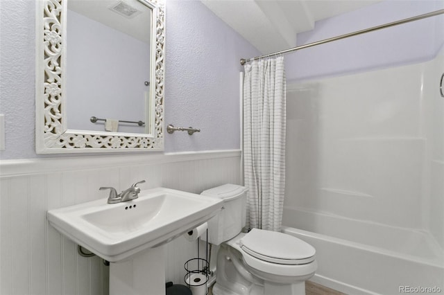 full bathroom featuring a wainscoted wall, visible vents, a sink, shower / bath combo with shower curtain, and toilet