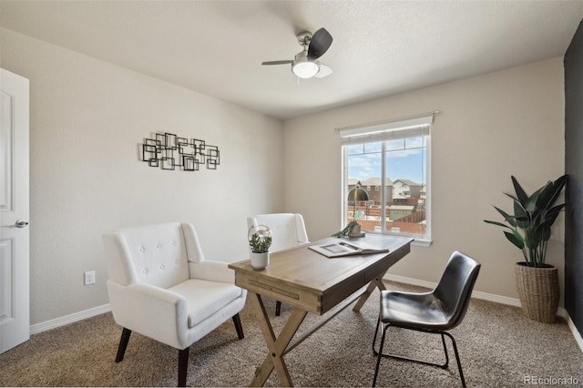 carpeted office space featuring ceiling fan and baseboards