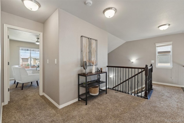 corridor with an upstairs landing, carpet floors, and baseboards