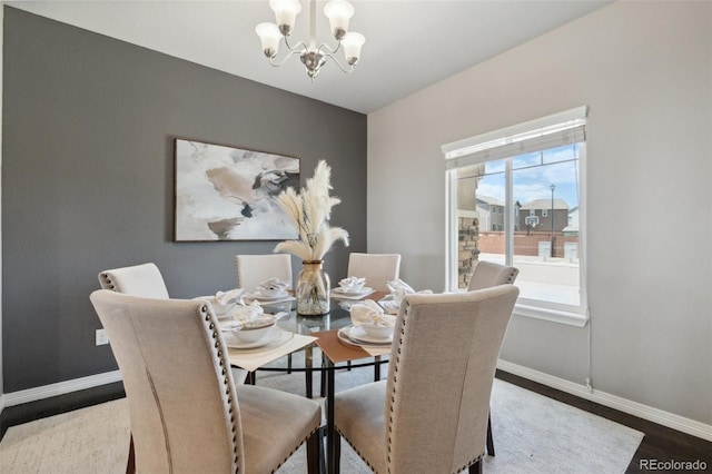 dining space featuring a chandelier, baseboards, and wood finished floors