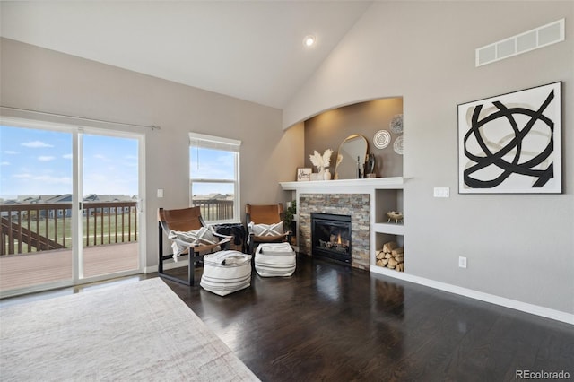 living area featuring wood finished floors, a stone fireplace, baseboards, high vaulted ceiling, and recessed lighting