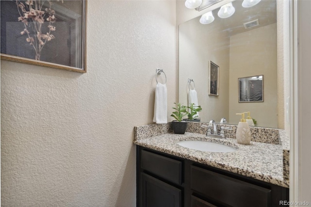 bathroom with a textured wall and vanity
