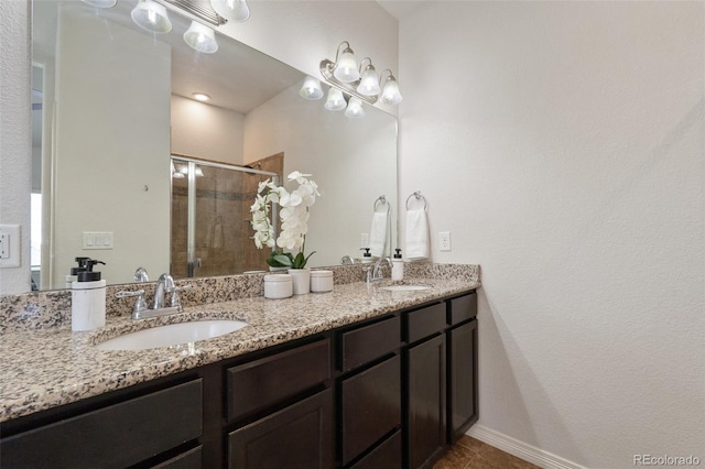full bath featuring a stall shower, double vanity, tile patterned flooring, and baseboards