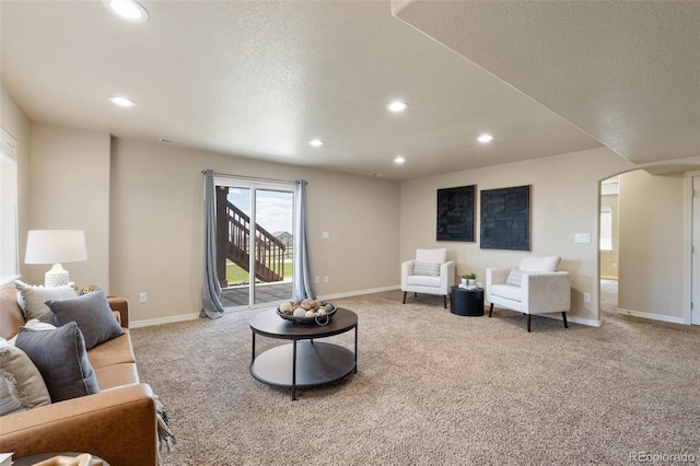 carpeted living area with recessed lighting, arched walkways, a textured ceiling, and baseboards