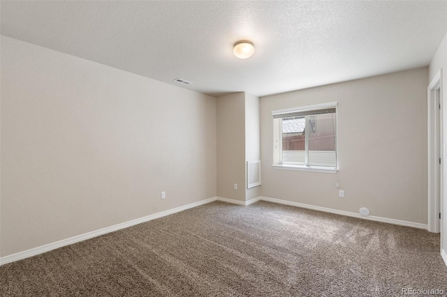 spare room featuring carpet, baseboards, and a textured ceiling
