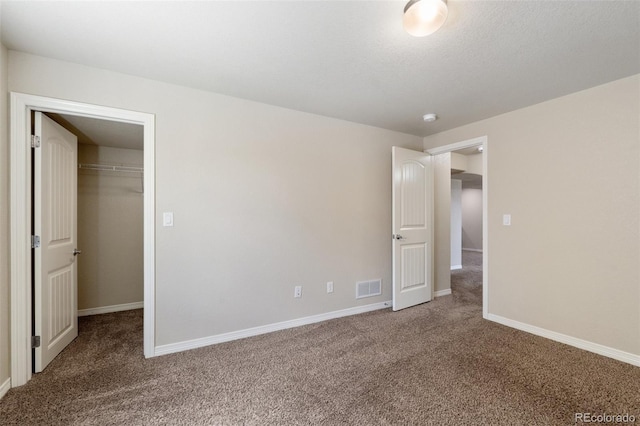 unfurnished bedroom featuring carpet floors, a spacious closet, baseboards, and a closet