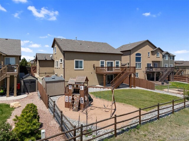 rear view of property with a playground, a storage shed, stairs, and stucco siding