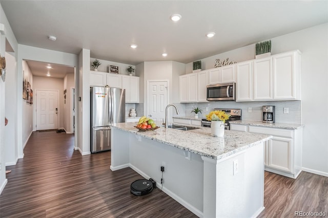 kitchen with sink, stainless steel appliances, white cabinets, and a center island with sink