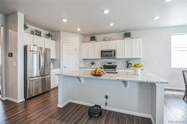 kitchen with a kitchen island with sink, white cabinets, and appliances with stainless steel finishes