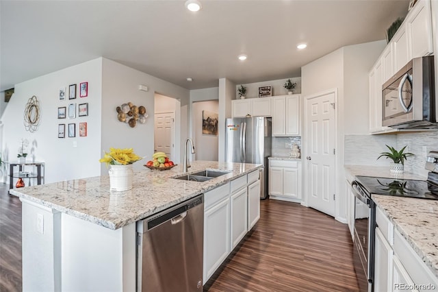 kitchen with appliances with stainless steel finishes, white cabinetry, an island with sink, sink, and light stone counters