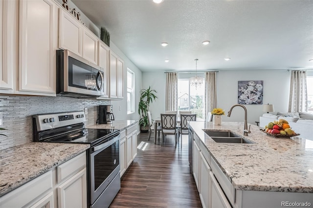 kitchen with sink, white cabinetry, a center island with sink, dark hardwood / wood-style flooring, and stainless steel appliances