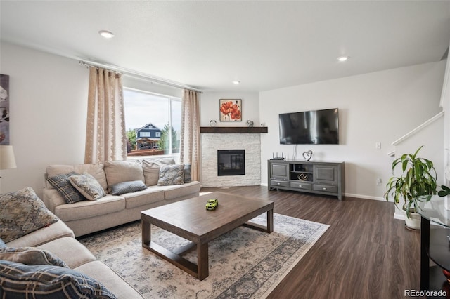 living room with dark hardwood / wood-style flooring and a stone fireplace