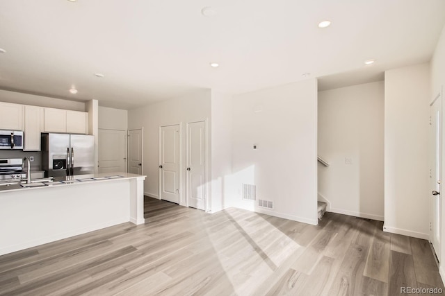 kitchen with white cabinets, light wood-type flooring, sink, and appliances with stainless steel finishes