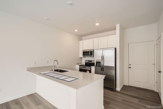 kitchen with white cabinetry, sink, stainless steel appliances, kitchen peninsula, and hardwood / wood-style floors