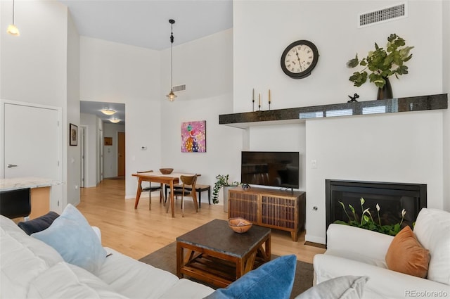 1438 Little Raven St Unit 407, Denver, CO 80202 - living room with a glass covered fireplace, a high ceiling, light wood-style floors, and baseboards