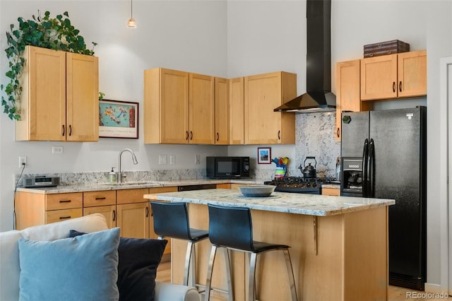 1438 Little Raven St Unit 407, Denver, CO 80202 - kitchen with wall chimney range hood, black appliances, a sink, light brown cabinets, and a towering ceiling