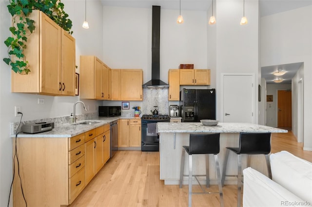 1438 Little Raven St Unit 407, Denver, CO 80202 - kitchen featuring black appliances, a towering ceiling, a sink, wall chimney range hood, and light brown cabinets
