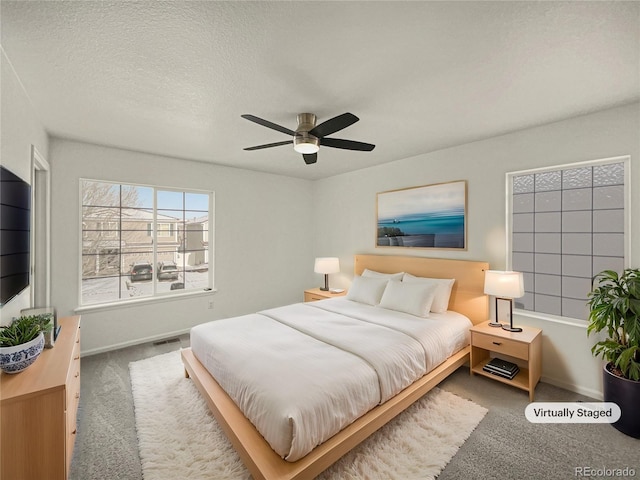 carpeted bedroom with ceiling fan and a textured ceiling