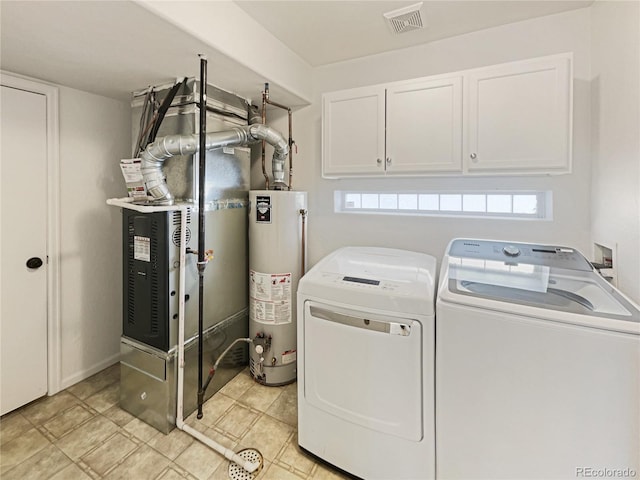 washroom with cabinets, heating unit, gas water heater, and washing machine and clothes dryer