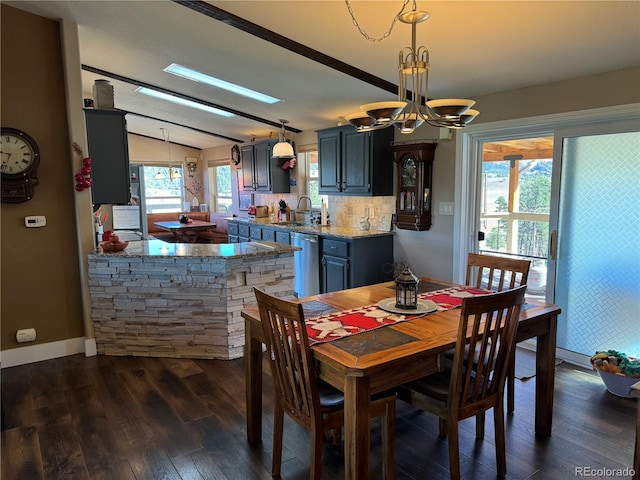 dining room with sink, a skylight, dark hardwood / wood-style flooring, and a chandelier