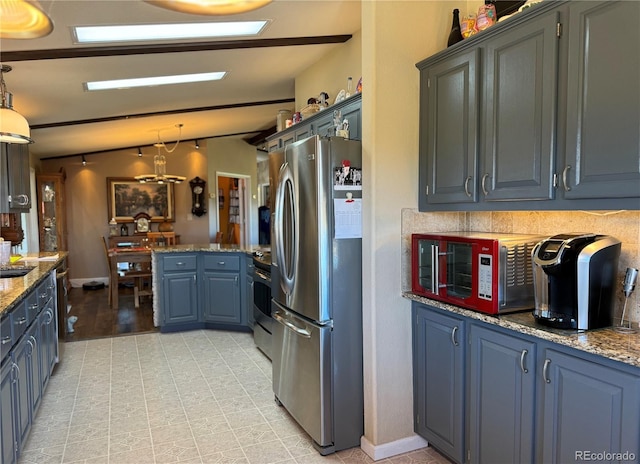 kitchen featuring lofted ceiling, appliances with stainless steel finishes, light stone counters, and decorative light fixtures