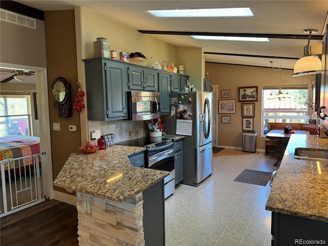 kitchen featuring appliances with stainless steel finishes, vaulted ceiling with skylight, tasteful backsplash, and a wealth of natural light