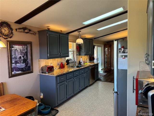 kitchen with tasteful backsplash, light stone counters, stainless steel appliances, sink, and decorative light fixtures