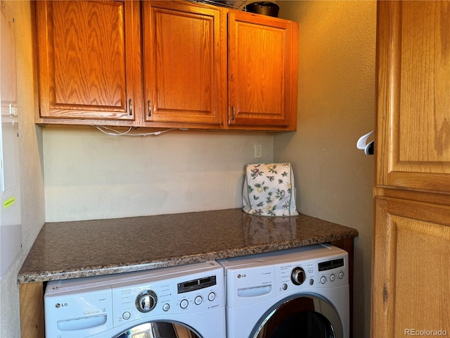 clothes washing area with washing machine and dryer and cabinets