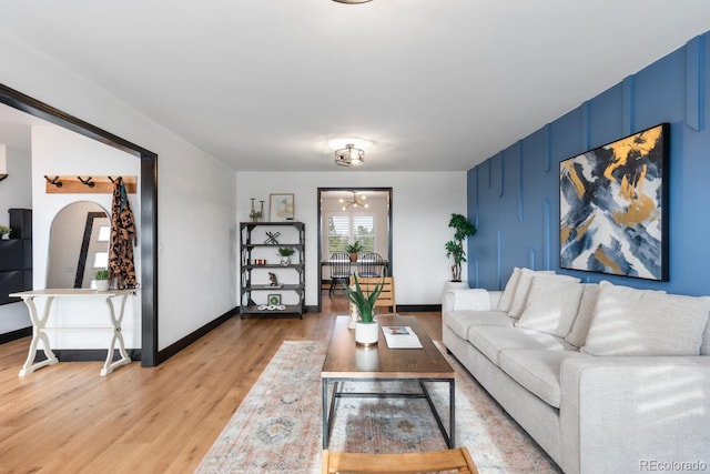 living room featuring arched walkways, light wood-type flooring, and baseboards