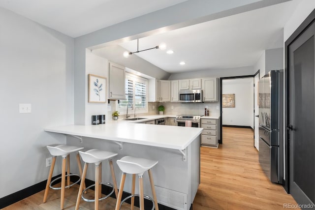 kitchen featuring visible vents, a breakfast bar area, a peninsula, stainless steel appliances, and a sink