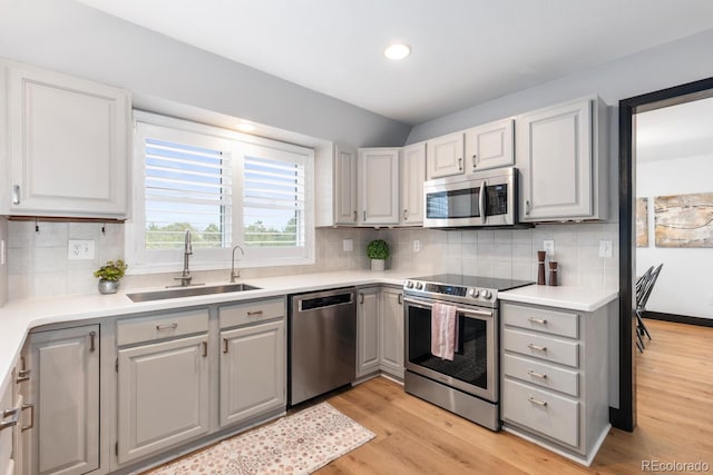 kitchen featuring a sink, light wood-type flooring, appliances with stainless steel finishes, and gray cabinets