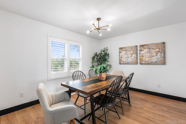 dining space with baseboards, light wood-type flooring, and an inviting chandelier