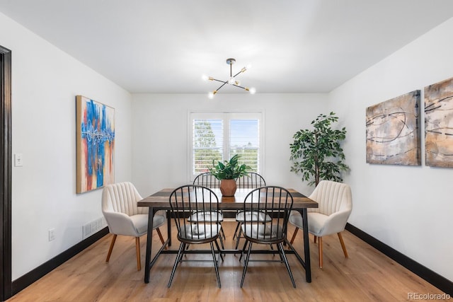 dining room with a notable chandelier, baseboards, visible vents, and light wood-type flooring